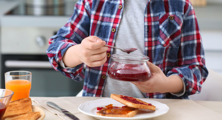 Person, die sich einen Toast mit Konfitüre vorbereitet