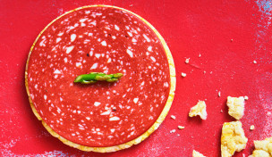 high-angle-view-of-a-slice-of-veggie-salami-on-a-rice-cake,-on-a-red-textured-surface-10x6