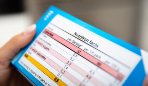 Nahaufnahme einer Frau, die Nährwertangaben auf der Box liest