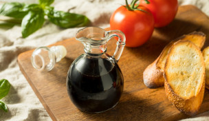 Karraffe mit Balsamico, Tomaten, Basilikum, Brot auf Holzbrett
