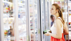 Frau schaut in ein Kühlregal im Supermarkt