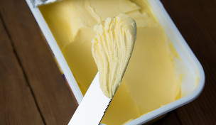 Margarine in einem Becher und ein Messer