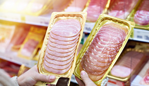 Zwei Hände halte je eine Packung Schinken zur Auswahl vor einem Supermarktregal Zwei Hände halte je eine Packung Schinken zur Auswahl vor einem Supermarktregal