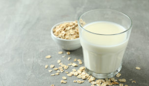 Glas mit Hafermilch, daneben kleine Schüssel mit Haferflocken