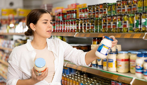 Verbraucherin mit Mayonnaiseglas im Supermarkt
