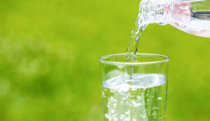 Wasser fließt aus Flasche in Glas