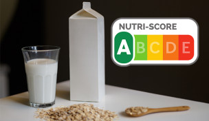 Glas und Tetrapack mit Hafermilch auf einem Tisch. Nutri Score mit Kateogorie A.