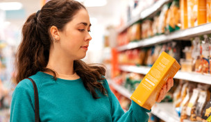 Junge Frau liest Zutatenverzeichnis vor einem Regal im Supermarkt