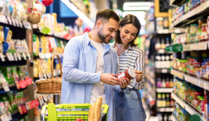 Paar im Supermarkt schaut sich die Rückseite eines Lebensmittels an