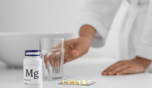 Magnesiumtabletten neben einem Glas Wasser auf einem Tisch