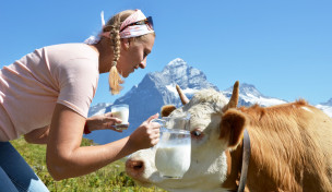 Frau mit Milchkrug und Kuh in den Bergen