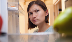 Frau schaut skeptisch in ihren Kühlschrank