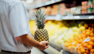 Mann hält eine Ananas im Supermarkt
