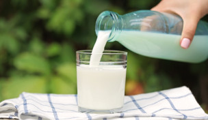 Milch wird aus einer Flasche in ein Glas gegossen