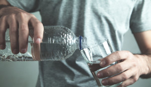 Person gießt Mineralwasser in ein Glas