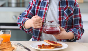 Person, die sich einen Toast mit Konfitüre vorbereitet