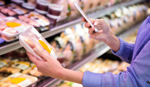 Verbraucherin prüft Verpackung mit Smartphone Verbraucherin prüft Verpackung mit Smartphone