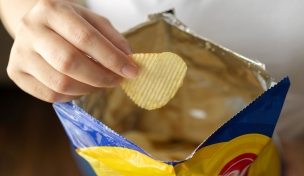 Hand mit Tüte und Kartoffelchips Hand mit Tüte und Kartoffelchips