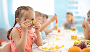 Kind sitzt an einem Tisch und isst