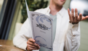 Mann liest Speisekarte und gestikuliert