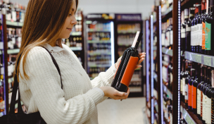 Frau betrachtet Weinflaschen Frau betrachtet Weinflaschen