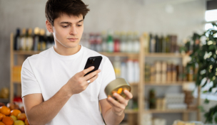 Mann mit Smartphone betrachtet ein Produkt Mann mit Smartphone betrachtet ein Produkt