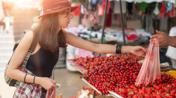 junge Frau kauft Kirschen an Marktstand