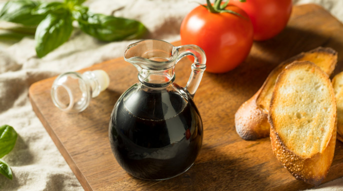 Karraffe mit Balsamico, Tomaten, Basilikum, Brot auf Holzbrett