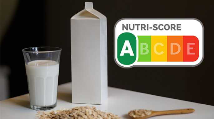 Glas und Tetrapack mit Hafermilch auf einem Tisch. Nutri Score mit Kateogorie A.