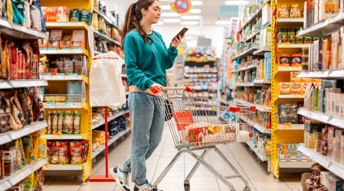 Frau mit Smartphone im Supermarkt