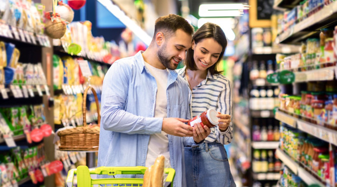 Paar im Supermarkt schaut sich die Rückseite eines Lebensmittels an