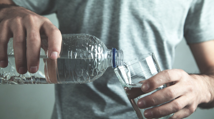 Person gießt Mineralwasser in ein Glas