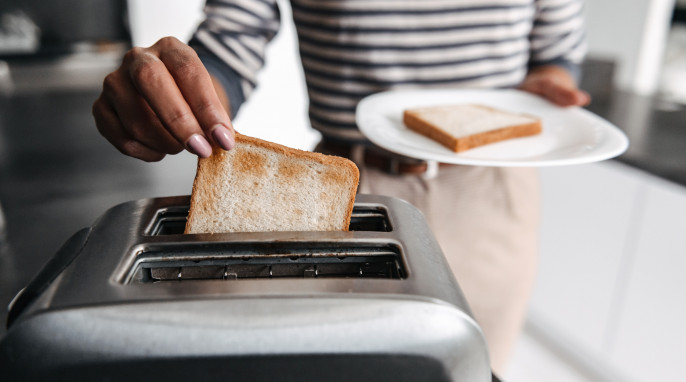 Frau nimmt Scheibe aus Toaster