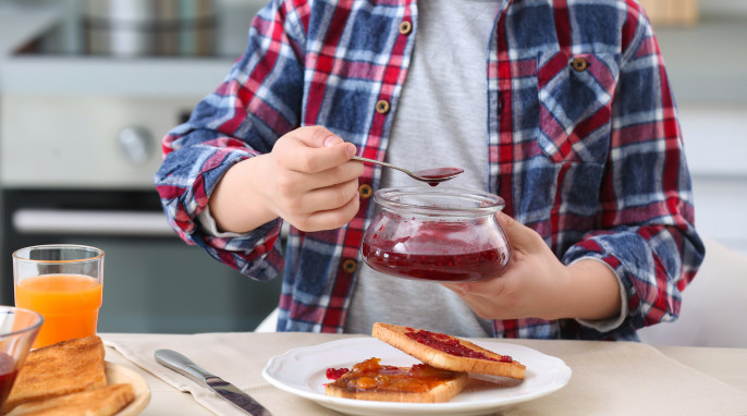 Person, die sich einen Toast mit Konfitüre vorbereitet