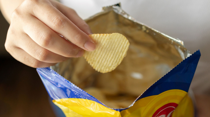 Hand mit Tüte und Kartoffelchips