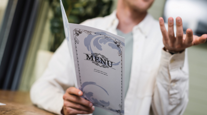 Mann liest Speisekarte und gestikuliert Mann liest Speisekarte und gestikuliert