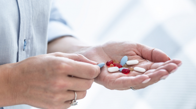 Person hält verschiedene Kapseln und Tabletten in der Hand Person hält verschiedene Kapseln und Tabletten in der Hand