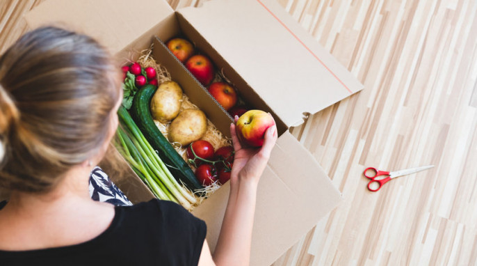 Frau packt Paket mit Obst und Gemüse aus