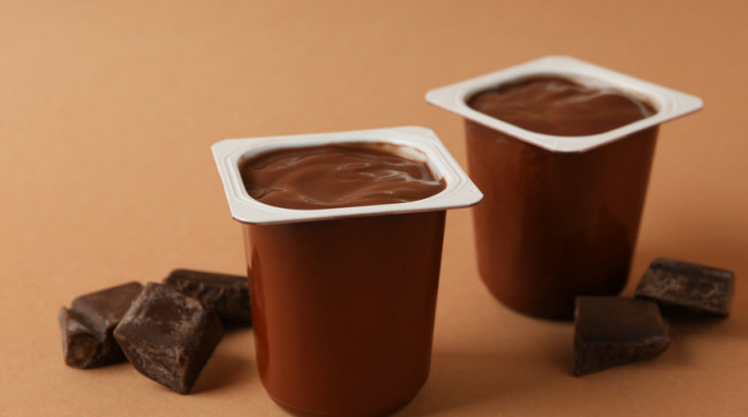 Plastics cups of chocolate yogurt on brown background