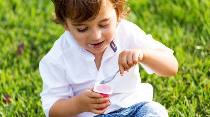 Junge der Joghurt im Park isst