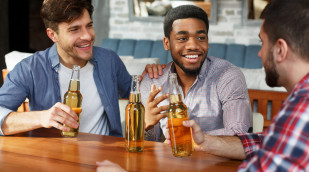 Männer sitzen am Tisch und trinken Biermischgetränk aus der Flasche; Quelle: milkos - 123rf.com