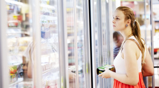 Frau schaut in ein Kühlregal im Supermarkt