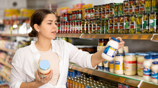 Verbraucherin mit Mayonnaiseglas im Supermarkt