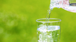 Wasser fließt aus Flasche in Glas
