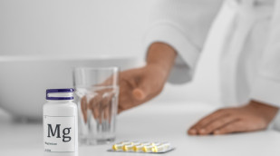Magnesiumtabletten neben einem Glas Wasser auf einem Tisch