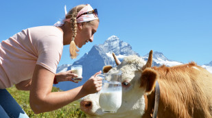Frau mit Milchkrug und Kuh in den Bergen
