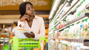 Frau denkt im Supermarkt nach