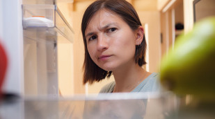 Frau schaut skeptisch in ihren Kühlschrank
