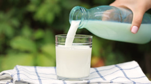 Milch wird aus einer Flasche in ein Glas gegossen