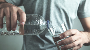 Person gießt Mineralwasser in ein Glas